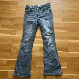 Grå bootcut jeans från ONLY - Snygga grå jeans från ONLY med bootcut-modell och klassisk femficksdesign. Jeansen har en medelhög midja och är tillverkade i mjukt denimtyg. Perfekta för dig som gillar en avslappnad men trendig look. Inga defekter, nästan nytt skick!