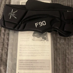 Full90 Premier svart huvudskydd - Svart huvudskydd från Full90, modell Premier F90. Designad med vadderade paneler och justerbara kardborreband för optimal passform. Perfekt för dig som spelar fotboll eller konståkning och vill ha extra skydd. Tillverkad i syntetmaterial för smidig känsla och bra ventilation.