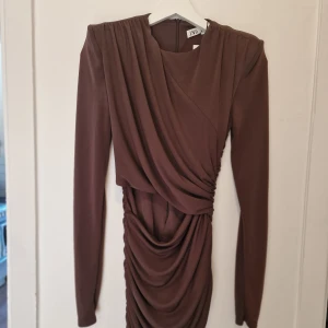 Brun draperad klänning från Zara - Supersnygg brun klänning från Zara med draperade detaljer och markerade axlar. 