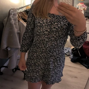 Blommig dress från Hollister XS - Supersöt svart shortsdress från Hollister med vita och gula blommor. Klänningen har offshoulder-modell, trekvartsärm. 