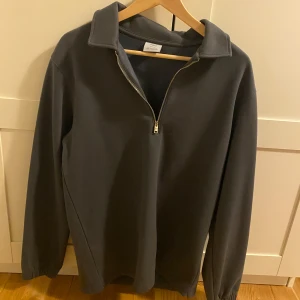 Mörkgrå fleece half zip från mango - Mysig mörkgrå fleece-tröja från mango med halv dragkedja och hög krage. Perfekt för kyliga dagar, har långärmad passform och enkel stil som funkar till allt. Regular fit och mjukt material som känns skönt mot huden.