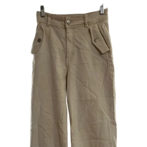 Beiga byxor med fickdetaljer - 🌟Beiga byxor i storlek 34 – tillverkade i ett tjockt men stretchigt och skönt material som sitter riktigt bekvämt. Snygga och lite annorlunda framfickor som ger byxorna det lilla extra. Fint skick och perfekta för vardag eller en mer avslappnad men stilsäker look. Säljes pga garderobsrensning. Skickas snabbt!📦