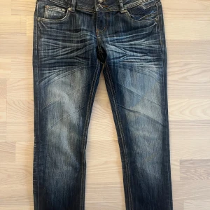 Kiss Me Jeans skinny jeans blå - Snygga skinny jeans från Kiss Me Jeans i mörkblå tvätt med slitningar och coola detaljer på fickorna. Jeansen har låg midja, dubbla knappar och dekorativa sömmar både fram och bak. Perfekta för dig som gillar en trendig och smal passform.