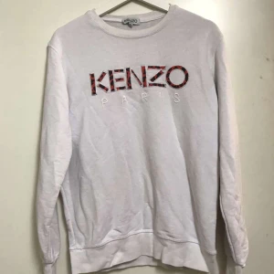 Vit Kenzo sweatshirt med tryck - Säljer en vit sweatshirt från Kenzo med stort logotyp-tryck i rött och svart framtill. Tröjan har rund halsringning och långa ärmar. Behöver dock stryckas.