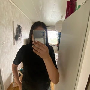 Svart glittrig topp - Snygg svart topp med glittrigt tyg och korta ärmar. Toppen har knappar bak i nacken som en extra detalj. Perfekt för dig som gillar stilrena plagg med lite extra shine. Pris kan diskuteras.