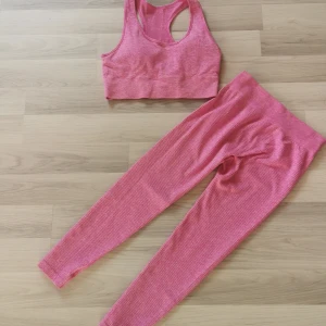 Rosa ribbad träningstopp och byxor  - Säljer en rosa ribbad träningstopp med brottarrygg. Toppen är croppad och har bred resår nedtill för extra stöd. Perfekt för gymmet eller yoga. Materialet är stretchigt och följsamt för maximal rörelsefrihet. 