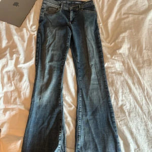 Blå low flare jeans XS/32 - Snygga blå jeans med low flare passform och låg midja från bikbok