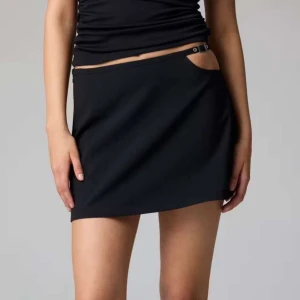 Svart minikjol med metallspänne - Supersnygg svart minikjol från Bik Bok med låg midja och coolt metallspänne i sidan. Kjolen har en clean och stilren look, perfekt för att skapa en trendig outfit💕