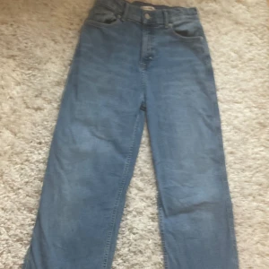 Blå jeans från Tommy Hilfiger - Klassiska blå jeans från Tommy Hilfiger med raka ben och femficksmodell. Byxorna har medel hög midja och är tillverkade i jeansmaterial med en snygg tvätt. Diskret Tommy Hilfiger-logga på bakfickan och patch bak i midjan.