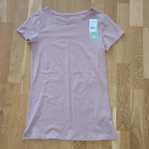 Ljusrosa t-shirt från KappAhl XS - Ljusrosa t-shirt från KappAhl i ekologisk bomull. Helt ny, prislappen kvar. Nypris 99 kr. 