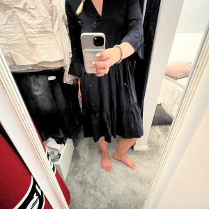 Svart volangklänning från Saint tropez - Svart klänning från Saint med v-ringning, volangdetaljer och trekvartsärm. Modellen är lös och har en flowy passform med flera lager i kjolen. Perfekt för dig som gillar en enkel men ändå chic look. Perfekt för sommaren, den är tunn och luftig men ändå fin så den passar till både vardag och middagar/fest😊💕💕