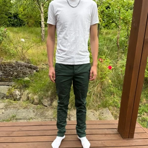 Mörkgröna chinos från Lacoste - Snygga mörkgröna chinos från Lacoste i slim fit-modell. Byxorna har klassiska fickor, diskret Lacoste-logga ovanför bakfickan och är tillverkade i bomull. Perfekta för dig som gillar stilrena och bekväma byxor med en clean look.
