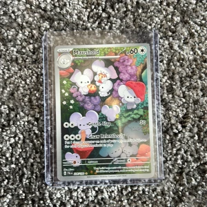 Maushold - Samlarvänligt Pokémonkort med Maushold, illustrerat i färgstark och lekfull stil. Perfekt för unga samlare och fans av Pokémon som vill utöka sin kortlek med en unik och charmig karaktär.