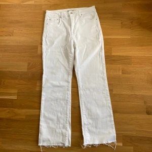 Vita raka jeans med råa kanter - Säljer ett par vita jeans med raka ben och snygga råa kanter nertill. Klassisk femficksmodell med hög midja och dragkedja. Perfekta för en clean och fräsch look, passar till allt. Materialet är bomull och de har en enkel, stilren vibe.