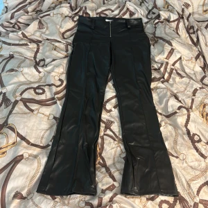 Svarta bootcut byxor i skinnlook Gina Tricot - Snygga svarta byxor från Gina Tricot i skinnimitation med bootcut-ben och hög midja. Byxorna har dragkedja framtill och hällor för bälte. Perfekta för dig som vill ha en edgy och trendig look. Helt nya och endast använda en eller två gånger! DM vid intresse!💕
