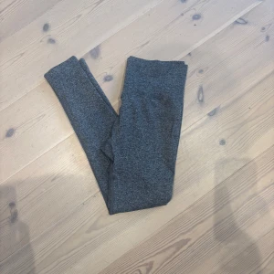 Mörkgrå leggings i stretchigt material - Mörkgrå leggings med smal passform och hög midja. Tillverkade i ett mjukt och stretchigt syntetmaterial som sitter skönt mot kroppen. Perfekta för chill eller träning, enkla att matcha med oversized hoodie eller crop top.