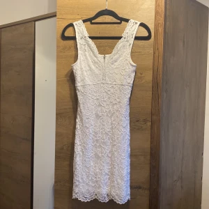 Vit spetsklänning från Cubus, stl 36 - Supersöt vit kortklänning från Cubus i storlek 36. Klänningen är ärmlös med v-ringning och täckt av vacker spets. Den har dragkedja i ryggen och en figurnära passform som framhäver siluetten. Perfekt för dig som vill ha en romantisk look!
