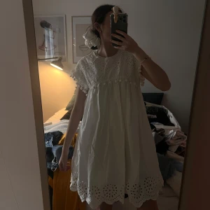 Vit klänning med spetsdetaljer - Charmig vit klänning med korta ärmar och vackra spetsdetaljer från Zara. Klänningen har en luftig passform och dekorativa bollar vid ärmsluten. Perfekt för sommarens alla tillfällen. Kommer passa en xs/s/m beroende hur pösig man vill att den ska vara 