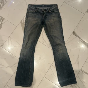 Blå jeans från 7 for All Mankind - Snygga blå jeans från 7 for All Mankind med en klassisk bootcut-stil. De har en låg midja och en lätt tvättad look som ger en jättesnygg look. Jättefina och sitter jöttebra. Har en vintage look vilket är mycket populärt nu och så är de i super kvalite. Passar mig som har storlek 34/w25/26 vanligtvis.❤️