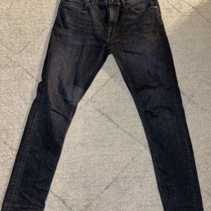 Svarta jeans från Tiger of Sweden - Snygga svarta jeans från Tiger of Sweden med klassisk design. De har en knapp och dragkedja framtill samt fem fickor. Perfekta för en stilren outfit. Storlek: 30/32