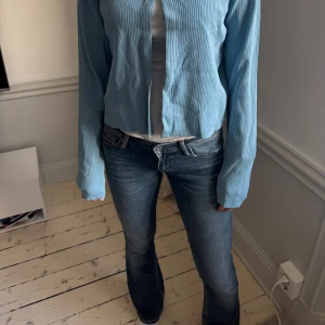 Blå bootcut jeans - Snygga blå bootcut jeans med en klassisk femficksdesign och knappgylf. Stretchiga och ger en vin figur. Lågmidjade  