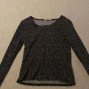 Blommig långärmad topp med knappar - Säljer en söt blommig topp med långa ärmar och knappar framtill. Perfekt för en avslappnad stil med ett fint mönster. Perfekt för våren😍