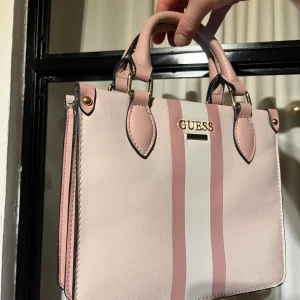 Rosa handväska från Guess - In great condition, maybe inside need a little more attention but other parts are great.  Medium size 