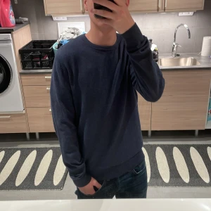 Stickad tröja  - Säljer en stilren mörkblå tröja från Dressmann i Supima bomull. Tröjan har en klassisk rund hals och långa ärmar, perfekt för en avslappnad look. Passar bra till jeans. Mvh 