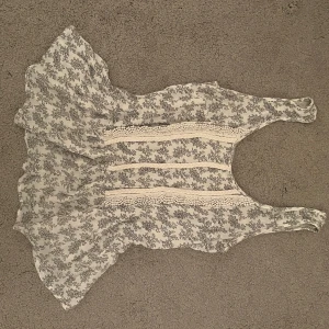 Blommig ärmlös topp från Reserved - Säljer en söt blommig topp från Reserved i storlek 34. Toppen är ärmlös med spetsdetaljer framtill och har en luftig passform. Perfekt för varma dagar!