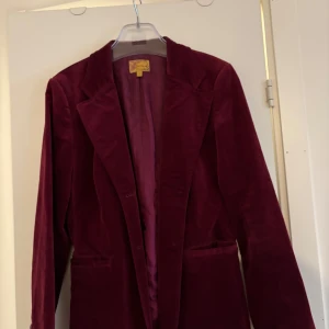 Vinröd sammets kavaj  från Jackpot - Snygg vinröd kavaj från Jackpot i en elegant design. Tillverkad i ett mjukt material med en klassisk krage och långa ärmar. Perfekt för att ge en stilfull touch till din outfit.
