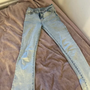 Ljusblå jeans med låg midja - Snygga ljusblå jeans med låg midja och flare-stil. De har en klassisk femficksdesign och stängs med dragkedja och knapp. Perfekta för en avslappnad look.
