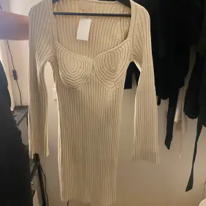 Säljer en stilren beige ribbad klänning från Hm med långärmad design och en unik detalj vid bysten. Perfekt för en chic look. 💫