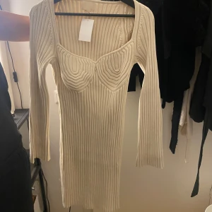 Beige ribbad klänning från Hm - Säljer en stilren beige ribbad klänning från Hm med långärmad design och en unik detalj vid bysten. Perfekt för en chic look. 💫