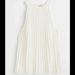 Vit ärmlös topp från H&M - Säljer en elegant vit ärmlös halterneck topp från H&M med plisserad design. Perfekt för somriga dagar eller speciella tillfällen. Toppen har en luftig passform och är tillverkad i ett lätt material.