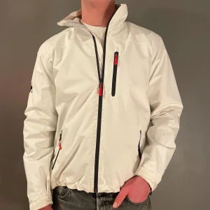 Vit seglarjacka från Helly Hansen - Säljer den här fina Helly Hansen jackan, perfekt inför våren under kyligare dagar. Jackan har lite smuts på sig men märks inte speciellt mycket när man har på sig den. Hör av dig vid minsta frågor. (Priset går att diskutera) 