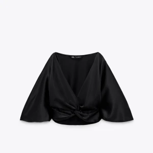 Svart v-ringad blus från Zara - Elegant svart blus från Zara med v-ringning. Blusen har vida trekvartsärmar och är tillverkad i ett mjukt, glansigt material som ger en lyxig känsla.