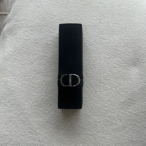 Rouge Dior läppstift 879 Forever - Rouge Dior läppstift i nyansen 879 Forever. Snygg mörkröd färg med matt finish. Hylsan är svart med silverdetaljer och har den klassiska CD-loggan. Perfekt för att ge läpparna en elegant och intensiv look. Kommer utan förpackning, oanvänd och otestad, om du köper fler av dessa läppstift kan jag tänka mig bättre pris. Rensning inför flytt. Vissa märken på själva skalet på läppstiftet kan förekomma då jag förvarat alla i samma låda 