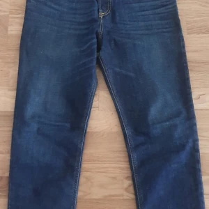 Blå jeansbyxor från Diesel D-Fining - Säljer ett par klassiska blå jeans från Diesel, modell 2005 D-Fining. Jeansen har raka ben, fem fickor och snygga kontrastsömmar. Perfekta för dig som gillar en tidlös denimlook. Märkeslapp på fickan och normal passform.