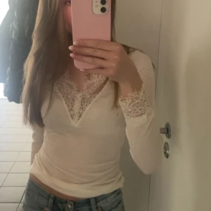 Vit långärmad topp med spetsdetaljer intimissmi - Säljer en vit långärmad topp med v-ringning och fina spetsdetaljer vid halsringning och ärmslut från  intimissmi. Använt fåtal gånger