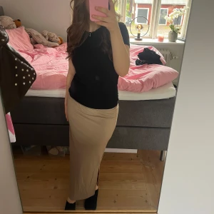 Beige ribbad långkjol - Säljer en beige ribbad långkjol med slits på sidan. Kjolen har en smal passform och är perfekt för dig som gillar en stilren och enkel look. Superskön och lätt att matcha med olika toppar.