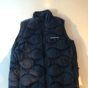 Mörkblå dunväst från Peak Performance - Oanvänd mörkblå väst från Peak performance. Perfekt för vår, sommar och höst. Storlek 176.
