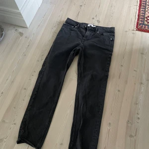Svarta jeansbyxor med rak passform - Säljer ett par svarta jeansbyxor med klassisk femficksdesign och rak passform. Byxorna har dragkedjegylf och knapp i midjan. Perfekta för dig som gillar en enkel och stilren look.