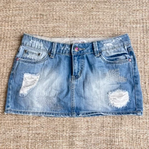 Ljusblå jeanskjol med slitningar - Säljer en ljusblå jeanskjol. Midjemåttet rakt över: 39cm, längd: 27cm 