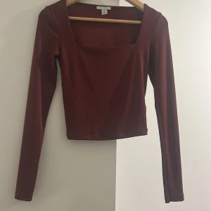 Vinröd  långärmad topp med fyrkantig ringning från Amisu - Säljer en vinröd långärmad topp från Amisu med snygg fyrkantig ringning. Toppen har en tight passform och är tillverkad i ett mjukt, stretchigt material. Perfekt att styla med jeans eller kjol.