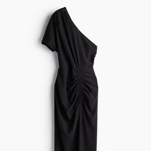 Svart oneshoulder klänning från H&M - Säljer en svart oneshoulder långklänning från H&M i storlek XS. Klänningen har en asymmetrisk axel, rynkade detaljer längs sidan och slits vid benen. Den har även en dragkedja vid midjan.Perfekt till sommaren