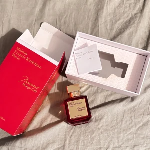 Maisan Francis Kurkdjian Baccarat Rouge 540 Extrait de Parfum - Lyxig parfym i en elegant röd glasflaska med guldfärgat lock. Kommer i en exklusiv röd kartong med guldtext. Doften är känd för sin intensitet och exklusivitet, och flaskan har en fyrkantig form med stilren etikett.