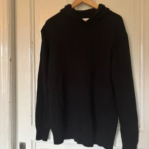 Svart ull hoodie  - Svart trendig hoodie från Vailent i mjuk merinoull. Klassisk modell med huva och långa ärmar. Perfekt för dig som gillar stilrena och bekväma plagg. Storlek L. 