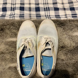 Vita sneakers med blå sula från Quicksilver - Säljer ett par vita sneakers med mesh-överdel och blå innersula från Quicksilver. Skorna har snörning och platt blå sula, perfekt för en avslappnad stil. Lätta och luftiga med rund tå. Missfärgade efter tvätt men extremt lite använda