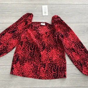 Röd och svart blus från VILA - Snygg röd och svart blus från VILA med leopardmönster. Blusen har långa ärmar och en luftig passform, perfekt för en trendig look. Materialet är lätt och bekvämt.