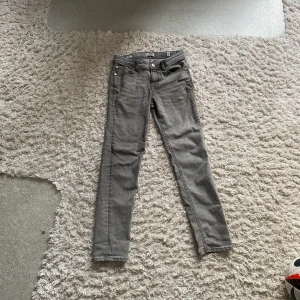 Gråa jeans från Jack & Jones - Snygga grå jeans från Jack & Jones i en klassisk straight fit. Det är storlek 158 och model Slim Glenn. Märket på baksidan är inte i det bästa skicket och små delar på fickorna är slitna. Perfekta för en stilren look samt passar med allt. 